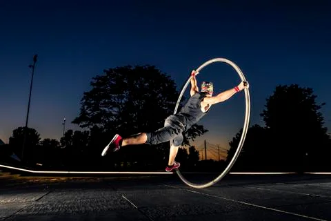 Cyr wheel performance session by young man at night. Stock Photos