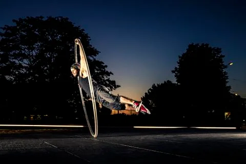 Cyr wheel performance session by young man at night. Stock Photos
