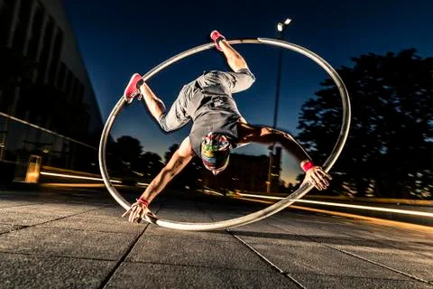 Cyr wheel performance session by young man at night. Stock-Fotos