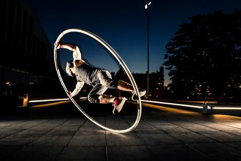 Cyr wheel performance session by young man at night. Stock Photos
