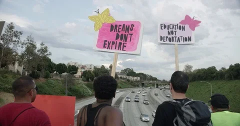 DACA supporters hold signs over 110 freeway during march from Echo Park Lake to Stock Footage 81574637