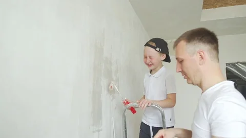 Dad and boy of 10 years old paints the walls in white, using a roller, Video stock 79524641