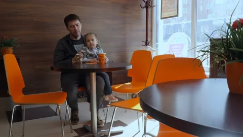 Dad and daughter are drinking coffee, a milkshake at the cafe. 库存影片 88764690