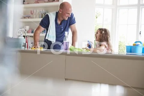 Dad and daughter cleaning the kitchen, looking at each other Stock Photos