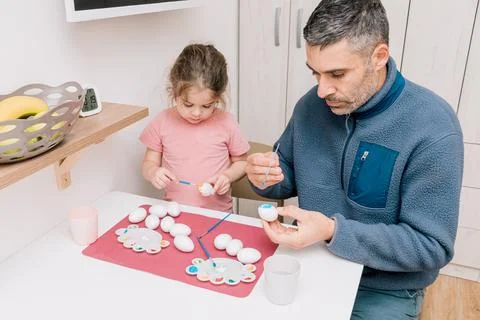 Dad and daughter drawing Easter eggs, man and girl spend time together for .. Stock Photos