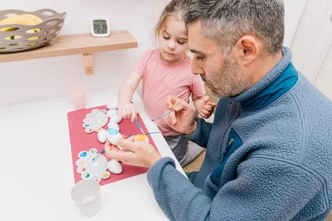Dad and daughter drawing Easter eggs, man and girl spend time together for .. Stock Photos