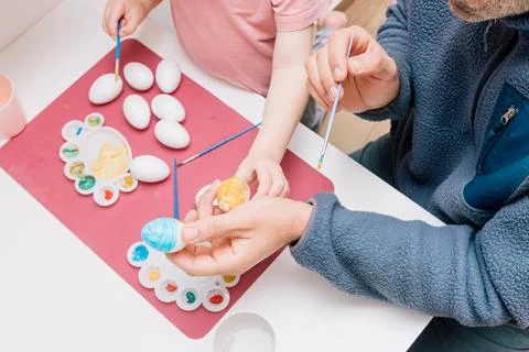 Dad and daughter drawing Easter eggs, man and girl spend time together for .. Stock Photos