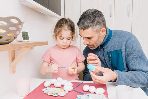 Dad and daughter drawing Easter eggs, man and girl spend time together for .. Stock Photos
