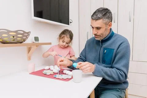 Dad and daughter drawing Easter eggs, man and girl spend time together for .. Stock Photos