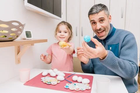 Dad and daughter drawing Easter eggs, man and girl spend time together for .. Stock Photos