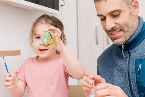 Dad and daughter drawing Easter eggs, man and girl spend time together for .. 스톡 사진