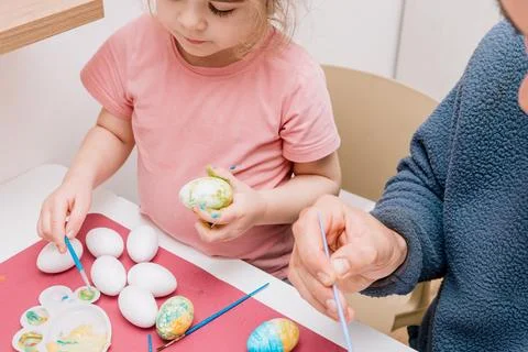 Dad and daughter drawing Easter eggs, man and girl spend time together for .. Stock Photos