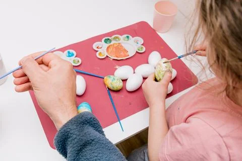 Dad and daughter drawing Easter eggs, man and girl spend time together for .. Stock Photos
