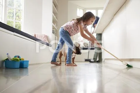 Dad and daughter sweep the kitchen floor together, side view Stock Photos