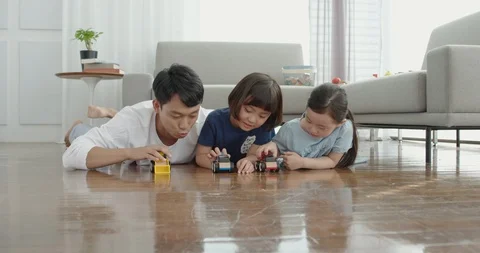 Dad and daughters are playing with toy cars Stock Footage 100941503