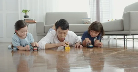 Dad and daughters are playing with toy cars Stock Footage 100941554