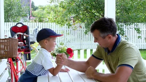 Dad and his four-year-old son play together in armwrestling, they are having fun Stock Footage 80443075