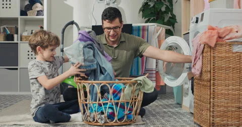 A dad and his son are cleaning clothes in the bathroom. They take the clothes 動画素材 200839882