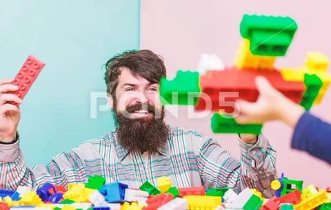 Dad and kid build plastic blocks. Child care and upbringing. Father son game Stock Photos
