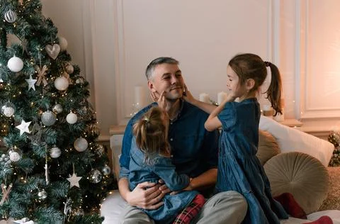 Dad and little daughters have fun together, sitting on the bed surrounded by  Stock Photos