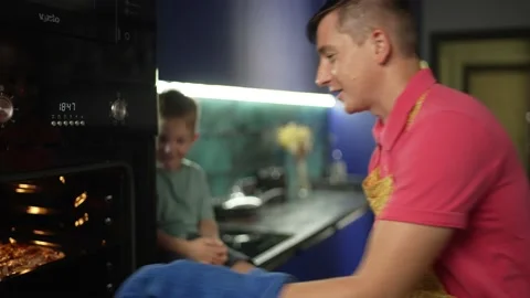 Dad and son are playing and cooking in the kitchen Stock Footage 221564031