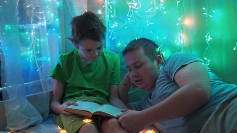 Dad and son are reading a book lying on the couch. into the light of the Stock Footage 170716914