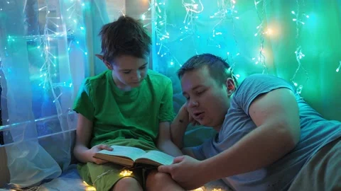 Dad and son are reading a book lying on the couch. into the light of the Stock Footage 171129961