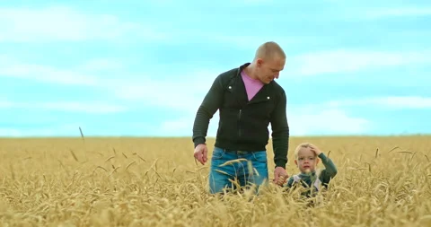 Dad and son are walking across the field, dad is holding his son by the hand Stock Footage 138965756