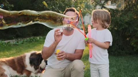 Dad and son blow bubbles on the lawn near the house. Stock Footage 217806952