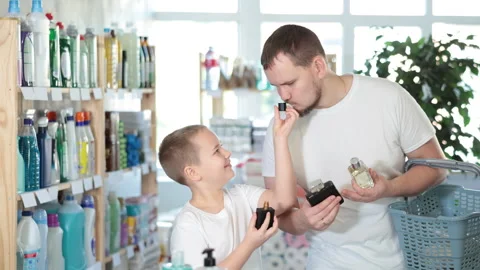 Dad and son client sniffs fragrance of perfume, chooses scent spray with Stock Footage 306981017