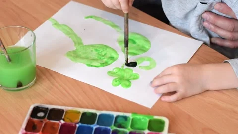 Dad and son drawing a leaf of clover on a white sheet of paper with watercolors. Stock Footage 150730561