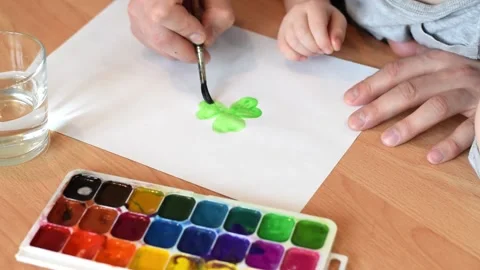 Dad and son drawing a leaf of clover with watercolors. Stock Footage 150730624