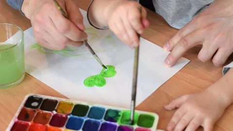 Dad and son drawing a leaf of clover on a white sheet of paper with watercolors. Stock Footage 150730655