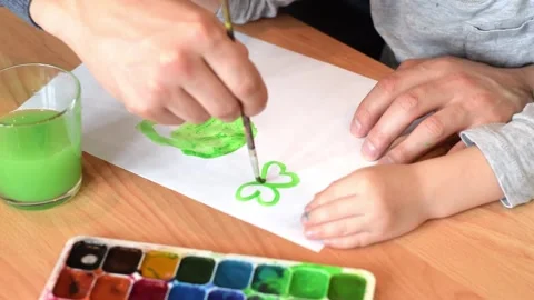 Dad and son drawing a leaf of clover with watercolors. Stock Footage 150730719