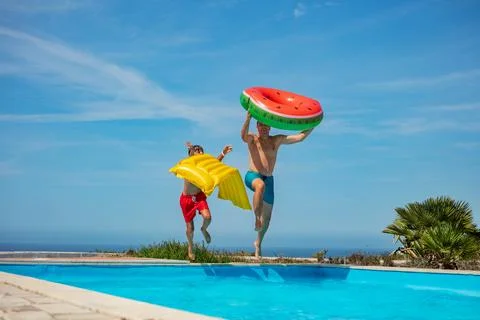 Dad and son with floaties jump to pool ready for summer fun Stock Photos