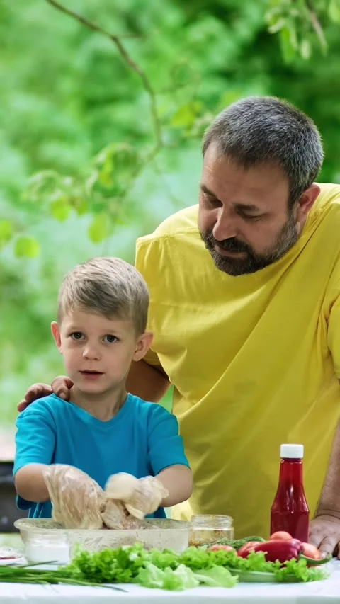 Dad and son marinating meat for grilling. Family picnic in the park. Stock Footage 305846758