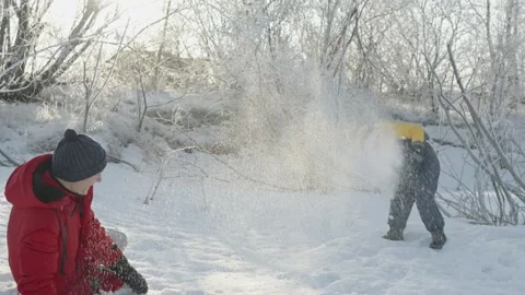 Dad and son play in winter, throwing snow at each other on a sunny frosty day Stock Footage 294345968