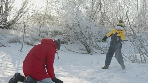 Dad and son play in winter, throwing snow at each other on a sunny frosty day Stock Footage 294346029