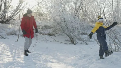 Dad and son play in winter, throwing snow at each other on a sunny frosty day Stock Footage 294346224
