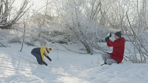 Dad and son play in winter, throwing snow at each other on a sunny frosty day Stock Footage 294346233