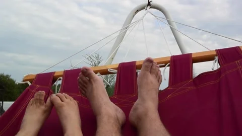 Dad and son relax and swing in red fabric hammock in courtyard of country house Stock Footage 264160799