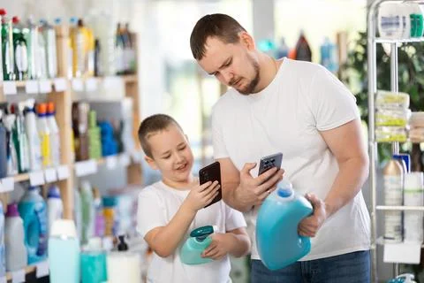 Dad and son scan barcode on packaging of laundry conditioner Stock Photos