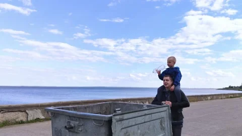 Dad and son throw the plastic bottle into the plastic collection container. Recy Video stock 153525673