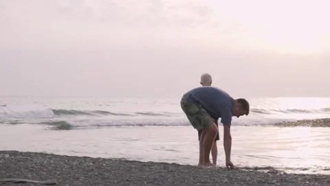 Dad and son throw stones in the sea at sunset on the beach of Sochi Video stock 142568280