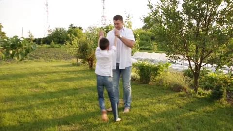 Dad and son walk together in the green garden near the house. Video stock 140366736
