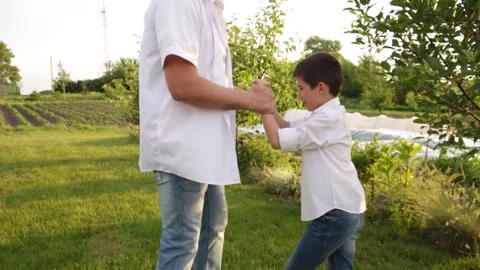 Dad and son walk together in the green garden near the house. Video stock 140366844