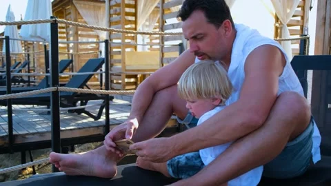 Dad and son watching something in a smartphone on the beach Stock Footage 200784587