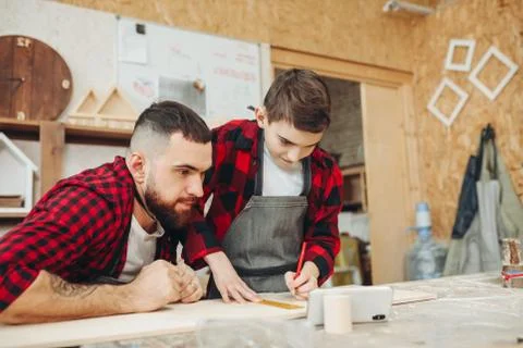 Dad and son in the workshop playing designing a model of a wooden plane Stock Photos