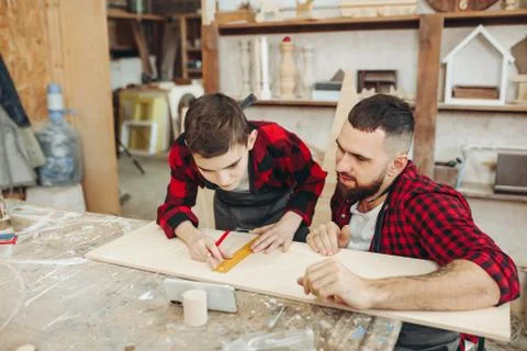 Dad and son in the workshop playing designing a model of a wooden plane Stock Photos
