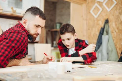 Dad and son in the workshop playing designing a model of a wooden plane Stock Photos
